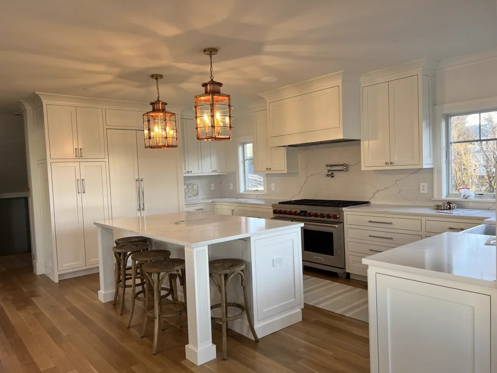 Finished white kitchen with island and lantern pendants in a rebuilt Harwich Port home