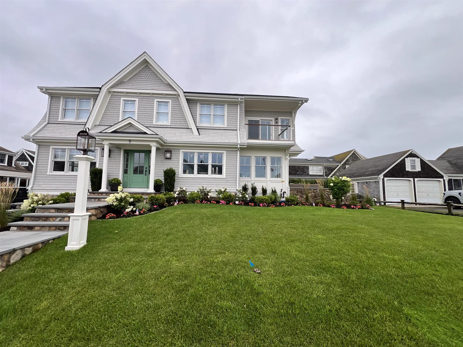 The finished Harwich Port home with gambrel roof, lawn, stone wall and lamp post