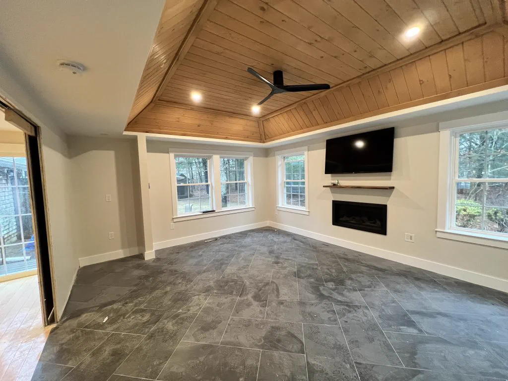 Family room with a wood-clad ceiling and tile floor in a finished Osterville addition
