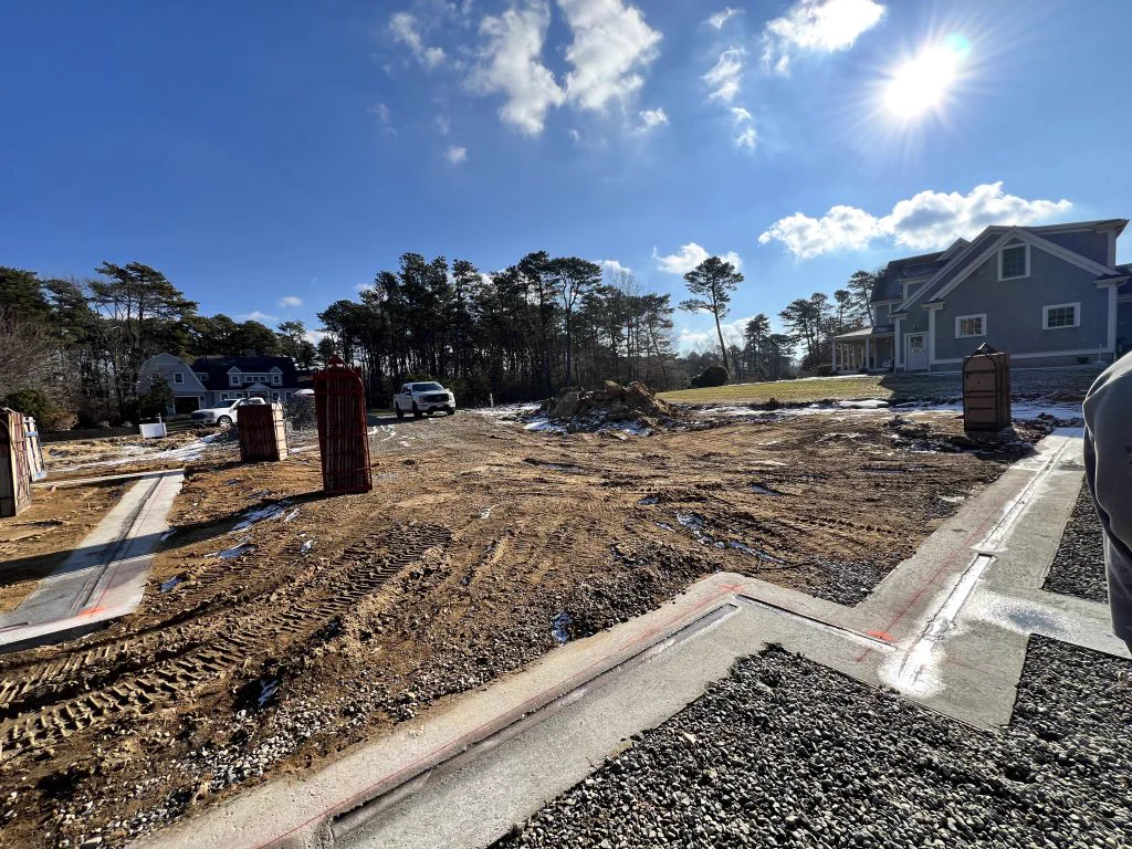Foundation walls poured on a cleared, sandy lot in Sandwich